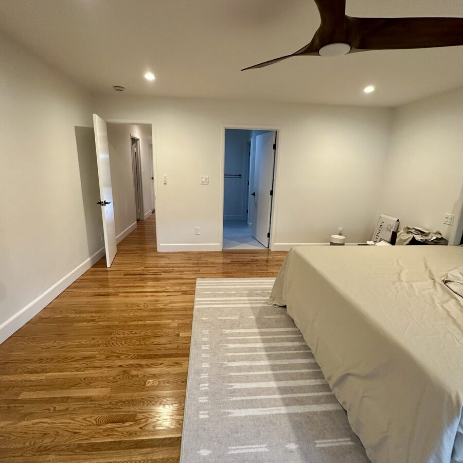 Expanded master bedroom in Birdland with hardwood floors and a hallway to the bathroom