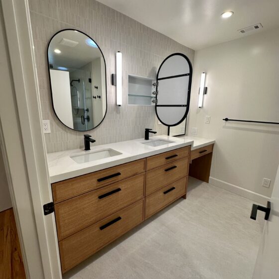 Remodeled bathroom vanity with wood drawers, oval mirror and skylight in a Birdland home