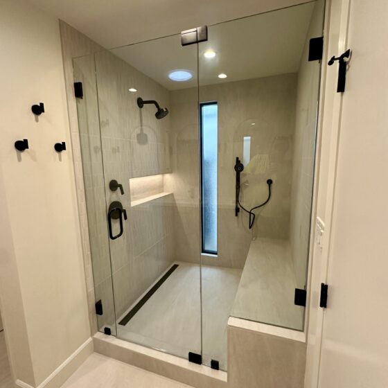 Walk-in glass shower with bench, niche and black fixtures in a Birdland master bathroom