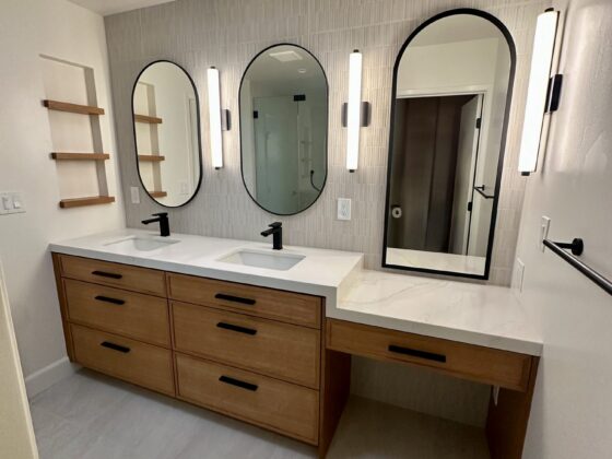 Master bathroom double vanity with wood drawers, arched mirrors and vertical sconces in a Birdland home