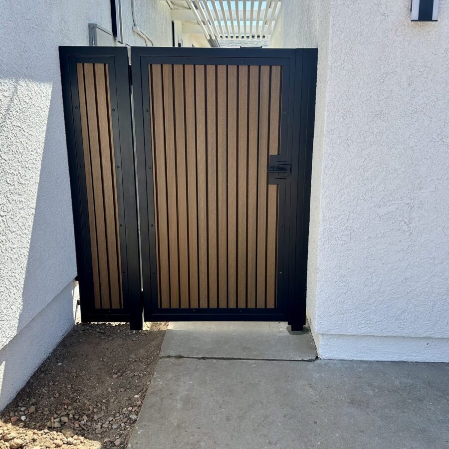 Custom-fabricated side gate with a black metal frame and slats on a Birdland home