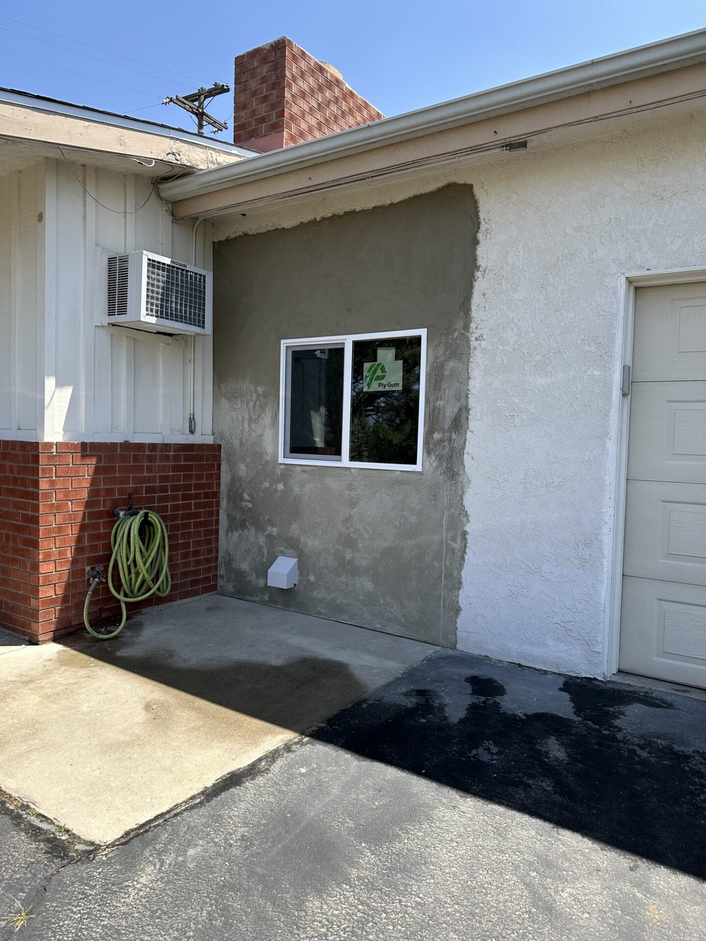 New window replacing the old entry door, with stucco patch in progress, on a Lakeside home
