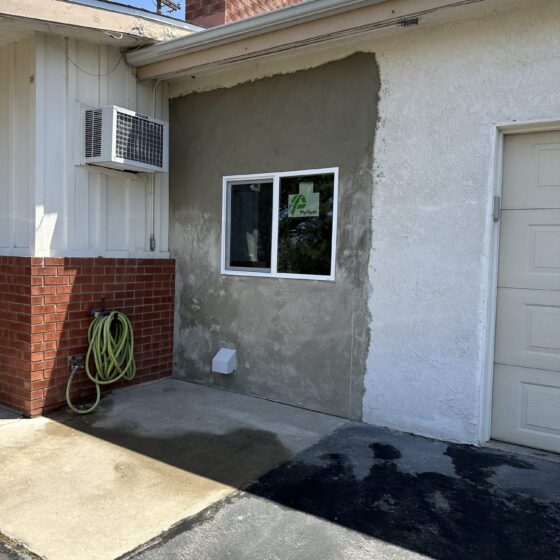 New window replacing the old entry door, with stucco patch in progress, on a Lakeside home