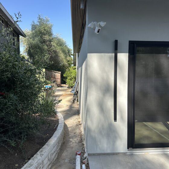 Side of a Scripps Ranch home addition with a black-framed glass door and smooth stucco