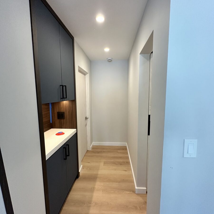 Hallway in a Scripps Ranch addition with built-in dark cabinets, a lit wood niche and large-format tile