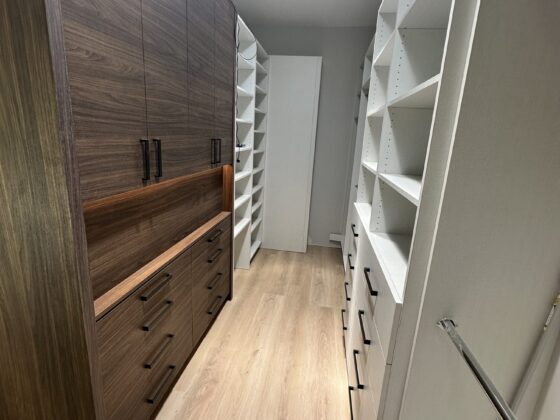 Walk-in closet with dark wood built-in drawers and white shelving in a Scripps Ranch home addition
