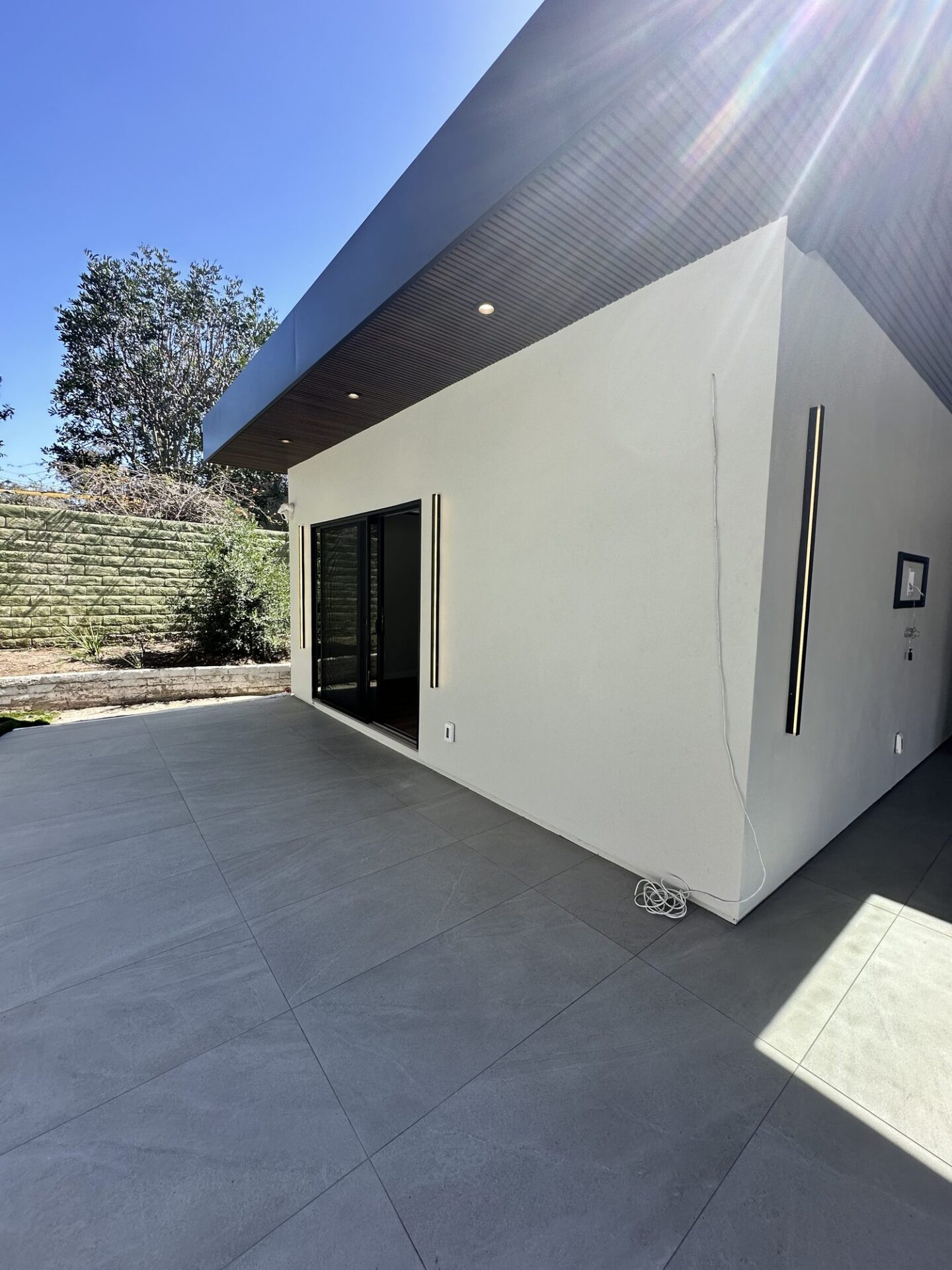 Scripps Ranch home addition with a covered patio, NewTechWood composite slat ceiling with skylights, and large-format tile